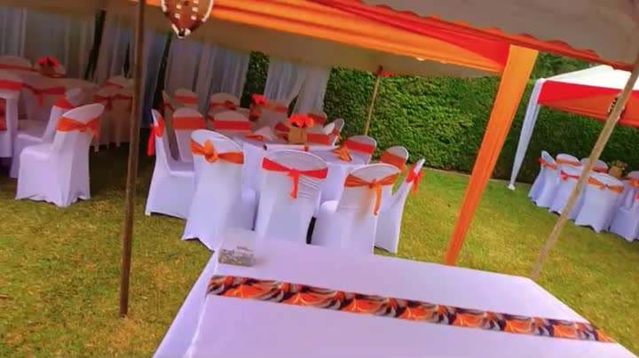 Tent with orange drapes and white covered chairs